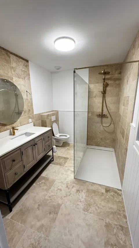 Salle de bains en travertin avec douche à l'italienne et meuble vasque en bois